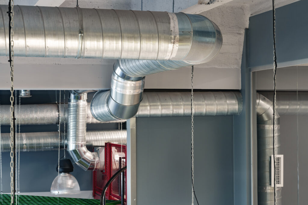 Silver Ventilation Pipes Hanging From The Ceiling Inside The Building